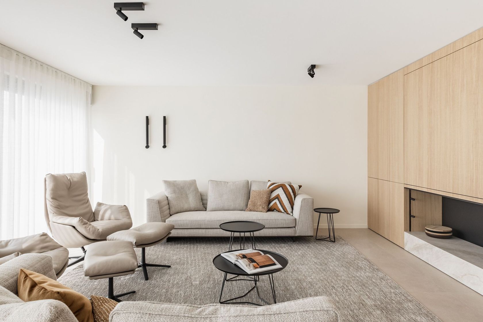 A Casalis wool rug grounding a calm, neutral living room with lounge seating and a timber wall unit, no people