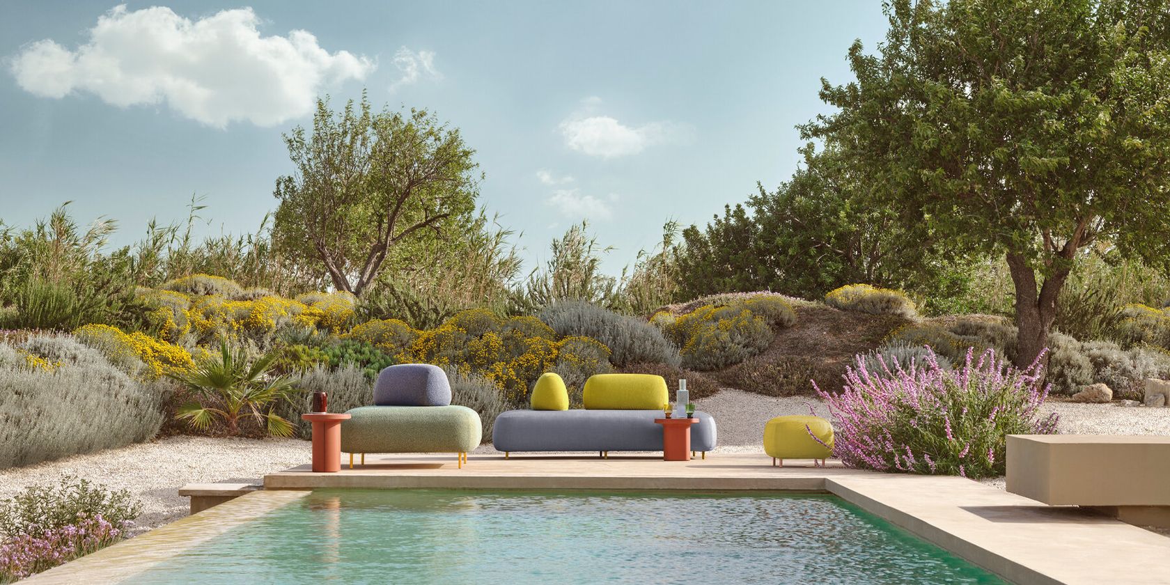 A Pedrali outdoor lounge setting beside a pool in a Mediterranean garden, no people